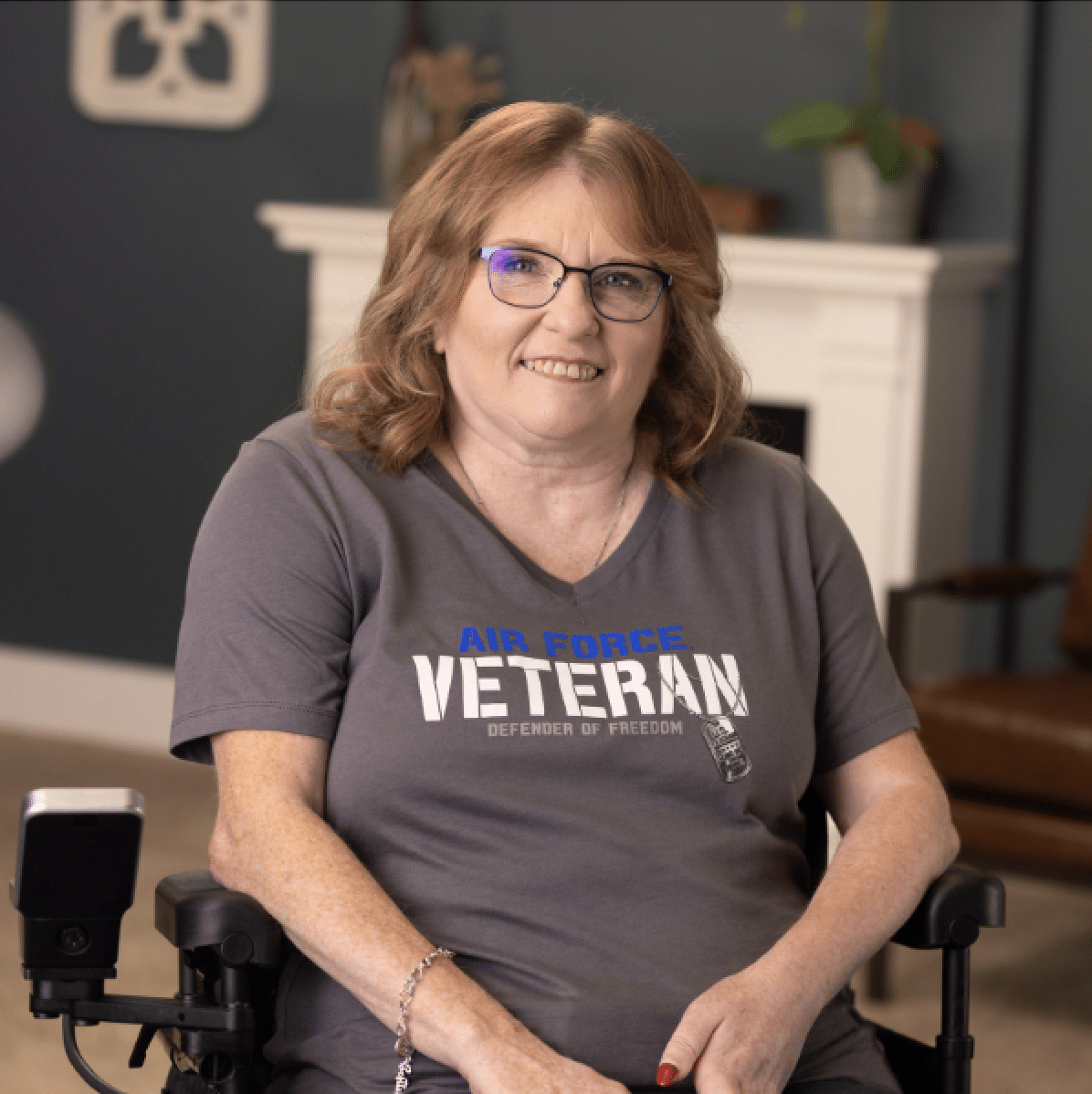 U.S. Air Force Veteran Tammy Smiles at the camera. She wears glasses and is in a power wheelchair.