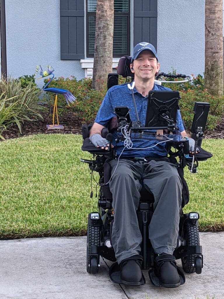 A legislative chamber with green carpeting, featuring dark wood desks and green chairs. The room has a large, decorated ceiling, an American flag, and a central elevated area with a podium and curtains.