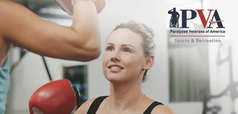 A woman in athletic wear boxes with a trainer in a gym. The Paralyzed Veterans of America (PVA) logo and the words "Sports & Recreation" are displayed in the upper right corner.