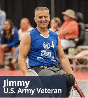 A smiling man in a wheelchair wearing a blue sports jersey with the number 4, participating in an athletic event. Text at the bottom reads "Jimmy, U.S. Army Veteran." Several people are blurred in the background.