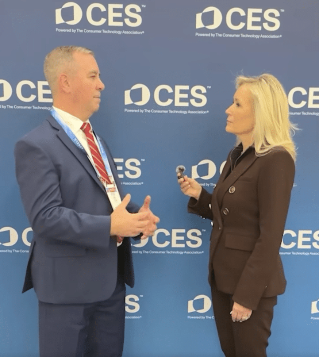 A man in a suit is being interviewed by a woman holding a microphone. They are standing in front of a blue CES event backdrop with white logos and text.