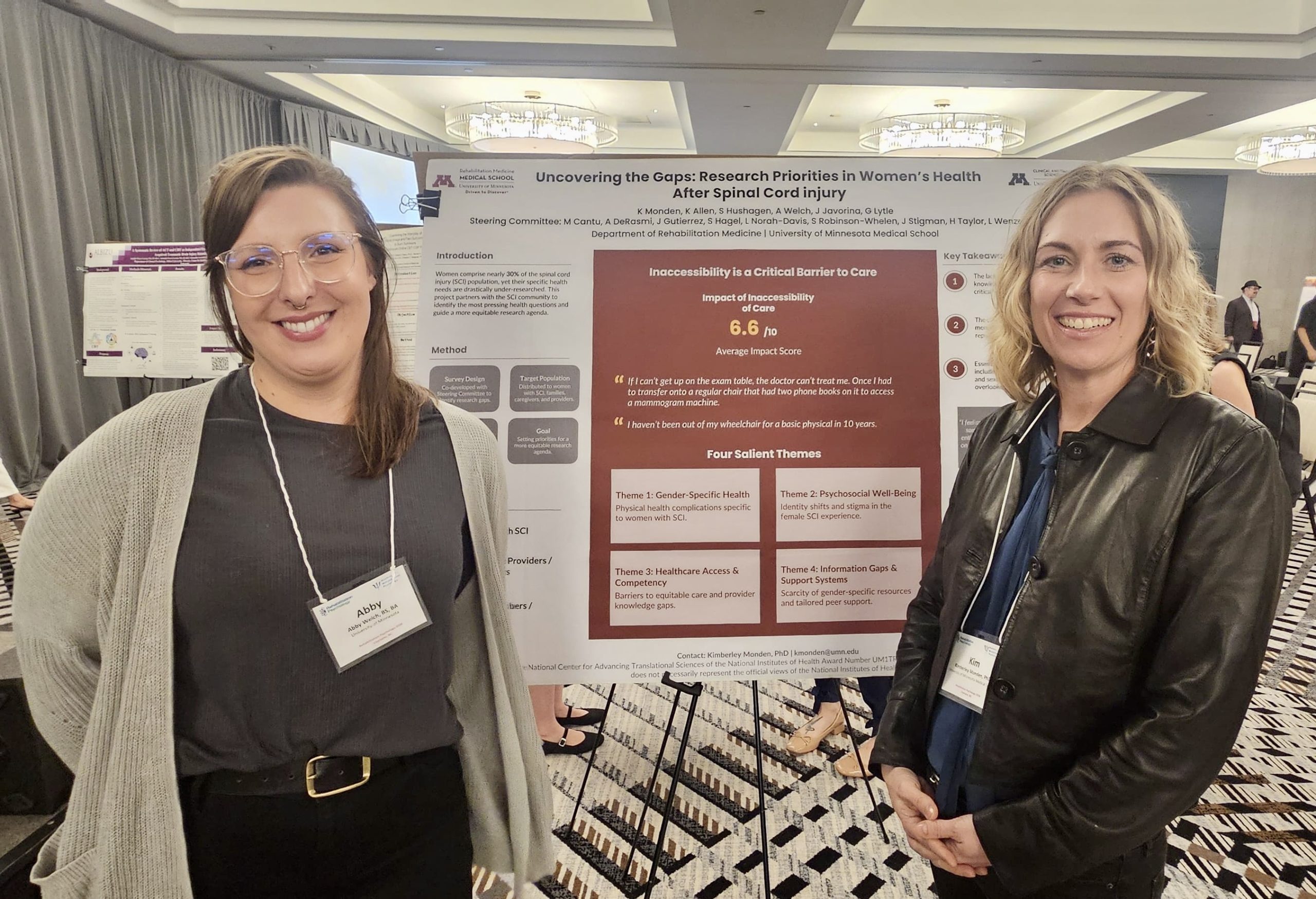 Two women stand smiling in front of a research poster about gaps in women's health after spinal cord injury at an academic conference. The poster includes data, charts, and key findings on inaccessibility and care.